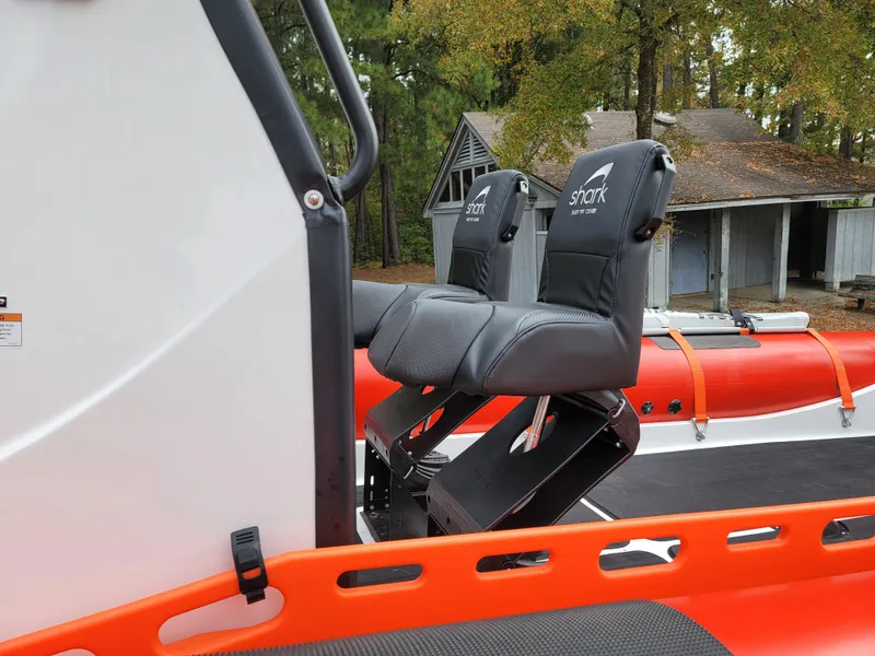 Slide: The Image of 2025 Fluid Watercraft SAR 23 boat on trailer, parked near a lake with autumn trees. - 0