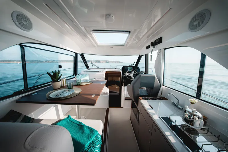 Slide: The Image of 2025 Beneteau Antares 9 interior, featuring modern kitchen and helm with ocean view. - 17