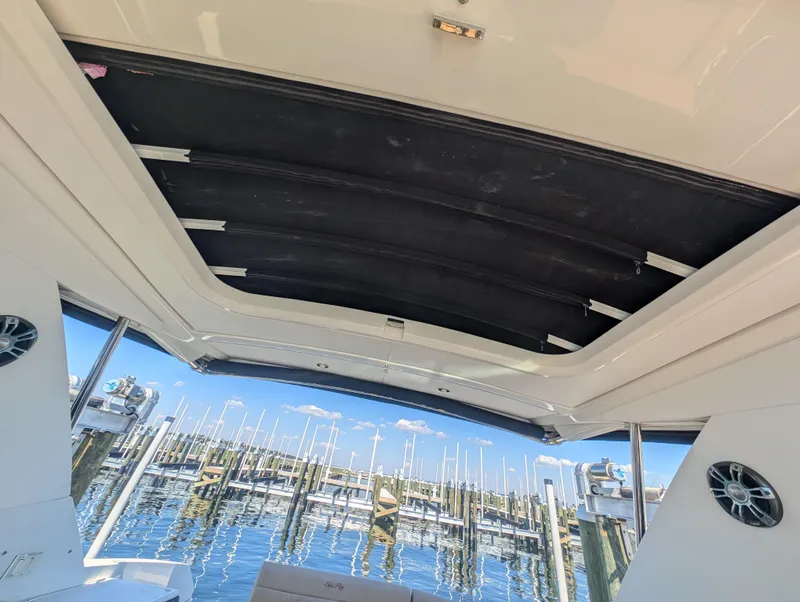 Slide: The Image of 2019 Sea Ray Sundancer 320 boat interior with open sunroof at marina. - 18