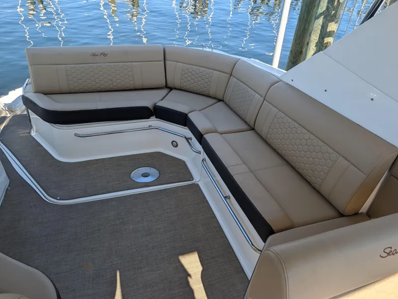 Slide: The Image of 2019 Sea Ray Sundancer 320 boat interior with beige seating and water view. - 7