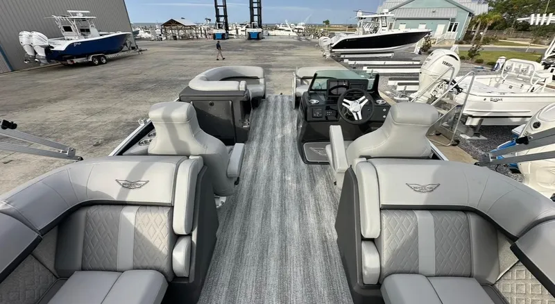 Slide: The Image of 2025 Bennington 22MFB Quad Bench pontoon boat with luxurious seating at a marina. - 13