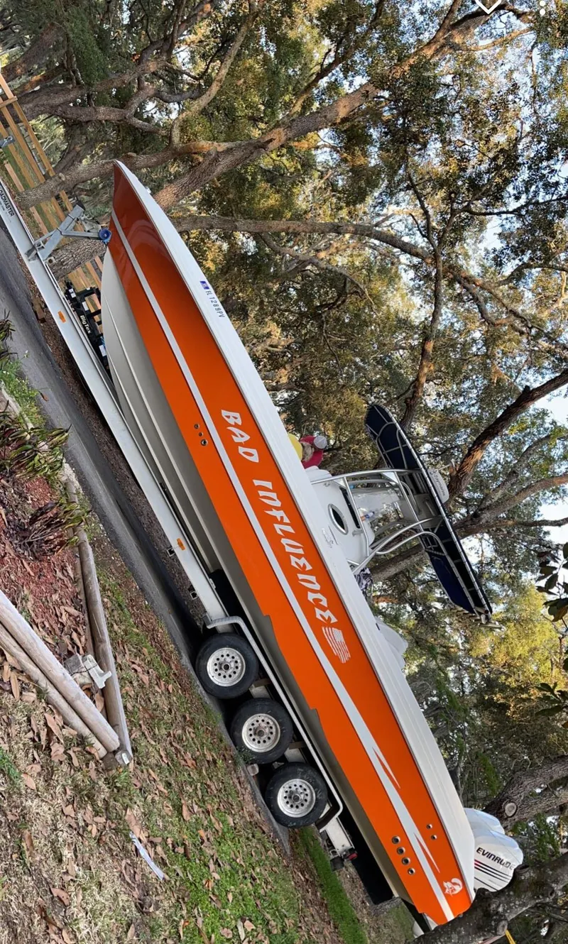 Slide: The Image of 2002 Wellcraft 32 Scarab Sport boat with orange and white design on a trailer. - 4