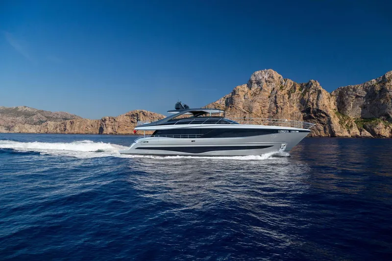 Slide: The Image of 2025 Princess Y95 Motor Yacht cruising near rocky coastline under clear blue sky. - 3