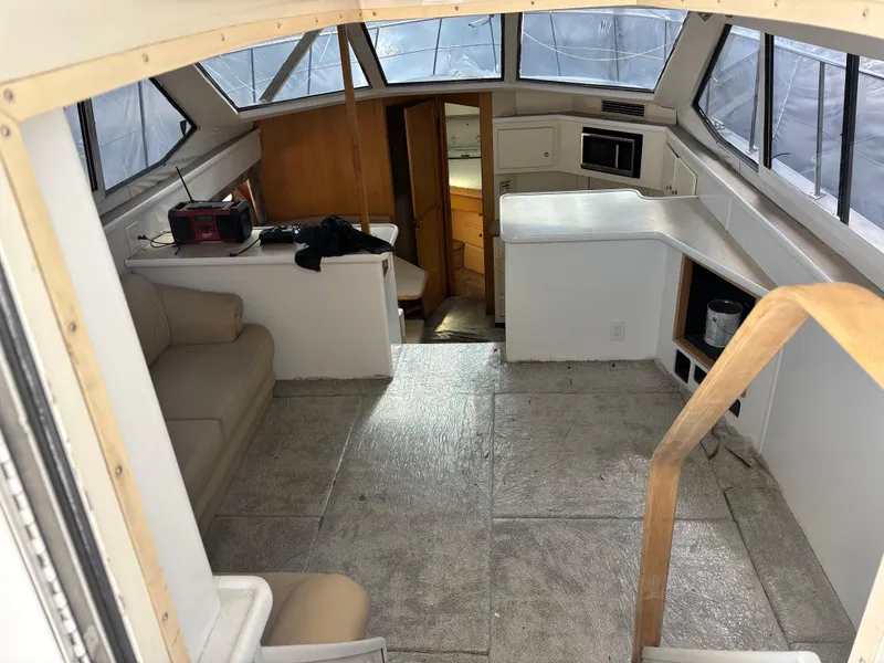 Slide: The Image of Interior of a 1997 Carver 405 yacht, featuring a spacious cabin with seating and kitchenette. - 11