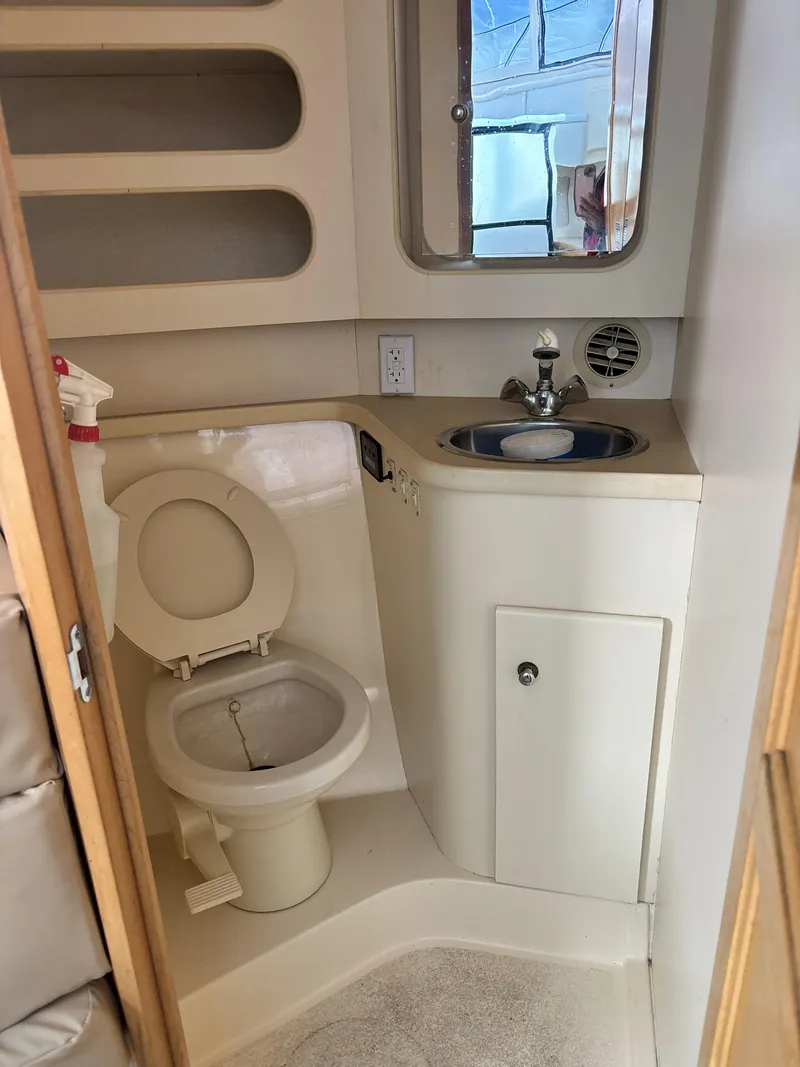 Slide: The Image of 1997 Carver 405 yacht bathroom with toilet, sink, and mirror. - 3