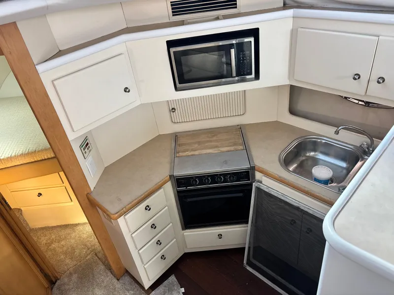 Slide: The Image of 1997 Carver 405 yacht kitchen with microwave, stove, sink, and storage cabinets. - 4