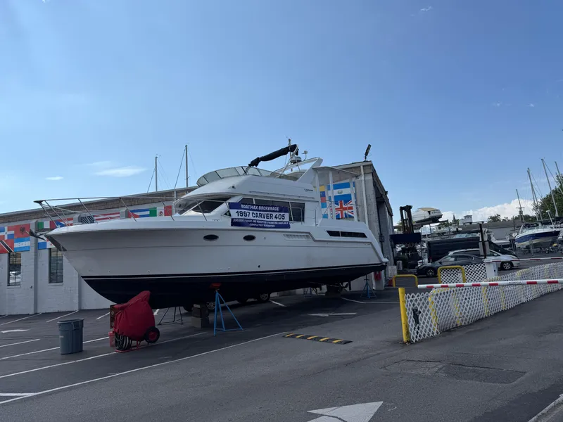 Slide: The Image of 1997 Carver 405 yacht displayed at a marina with international flags in the background. - 13