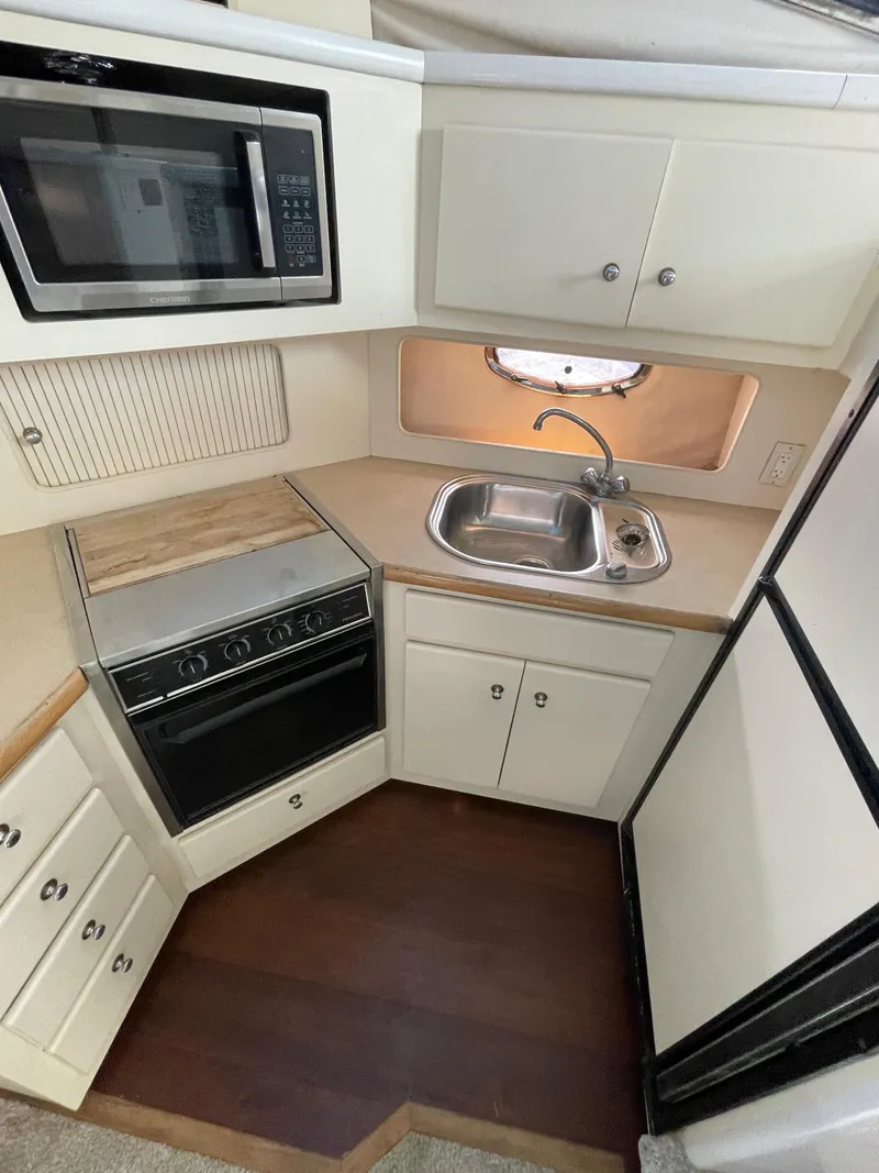 Slide: The Image of 1997 Carver 405 yacht kitchen with microwave, stove, sink, and cabinets. - 24
