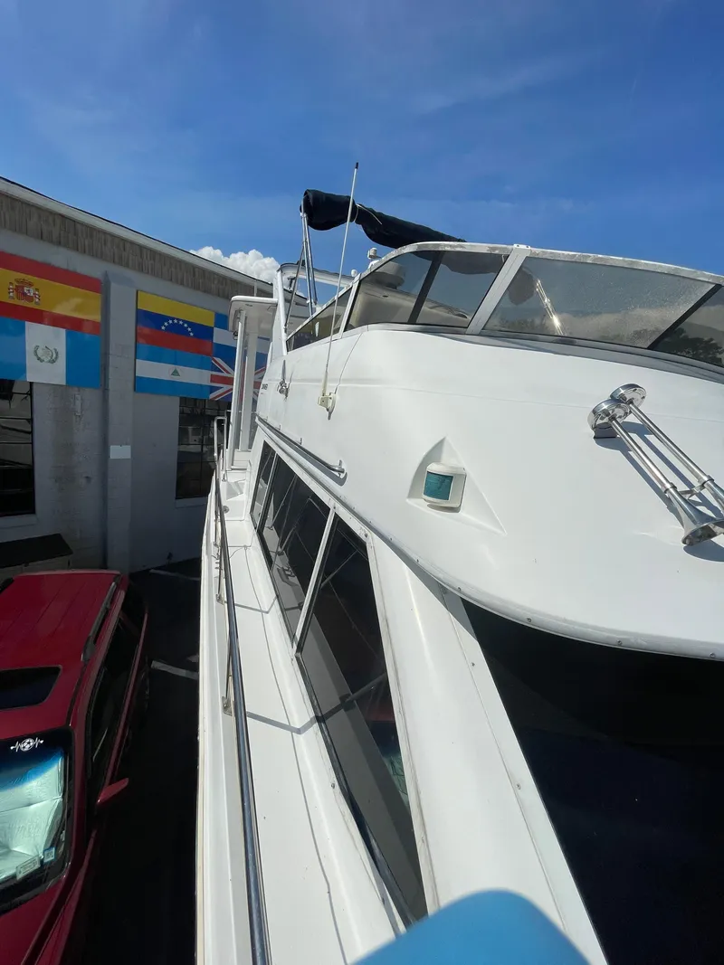 Slide: The Image of 1997 Carver 405 yacht docked near flags and a red vehicle. - 34