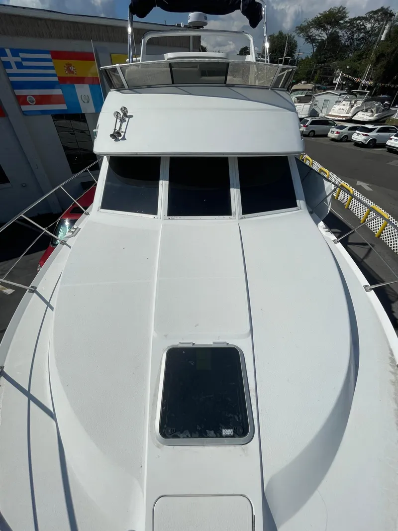 Slide: The Image of 1997 Carver 405 yacht, top view, docked near flags and other boats. - 35