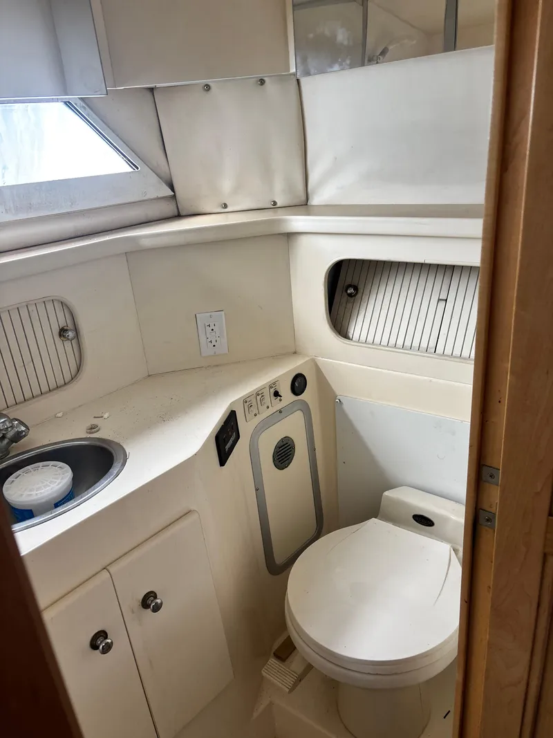 Slide: The Image of 1997 Carver 405 yacht bathroom with toilet, sink, and storage cabinets. - 7