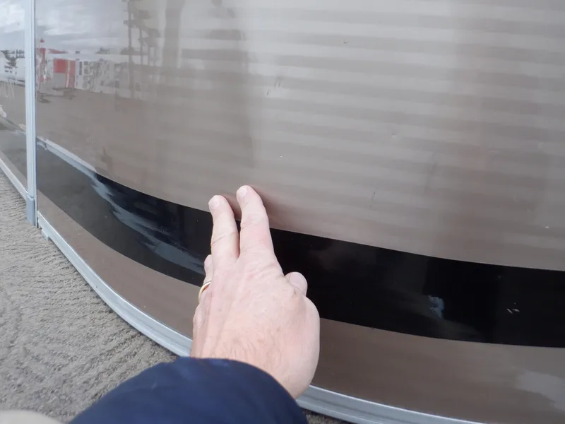 Slide: The Image of Close-up of a hand touching the side of a 2011 Bennington 22 SSL boat. - 18