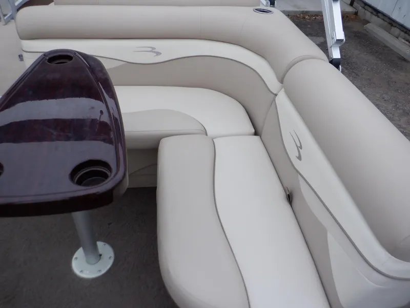 Slide: The Image of Bennington 22 SSL 2011 boat interior with beige seating and dark wood table. - 45