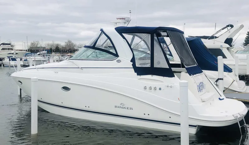 The Image of 2008 Rinker 330 Express Cruiser docked at marina, featuring sleek design and blue canopy. - 0
