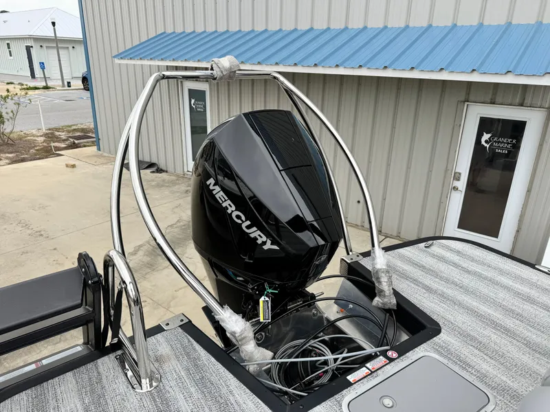 Slide: The Image of 2025 Bennington 22MSB boat with Mercury outboard motor, docked near a metal building. - 5