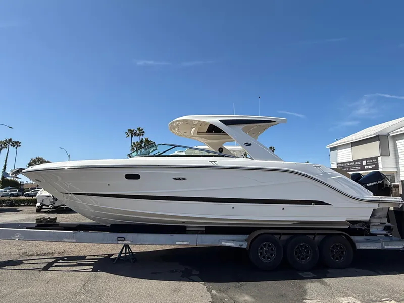 The Image of 2025 Sea Ray SLX 310 OB boat on trailer, sunny day, palm trees in background. - 0