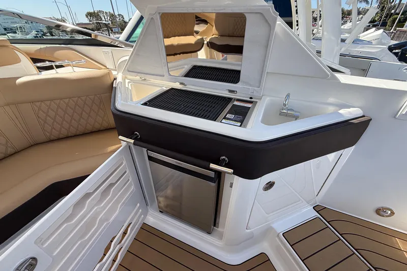 Slide: The Image of 2025 Sea Ray SLX 310 OB boat interior with kitchenette and seating area. - 10