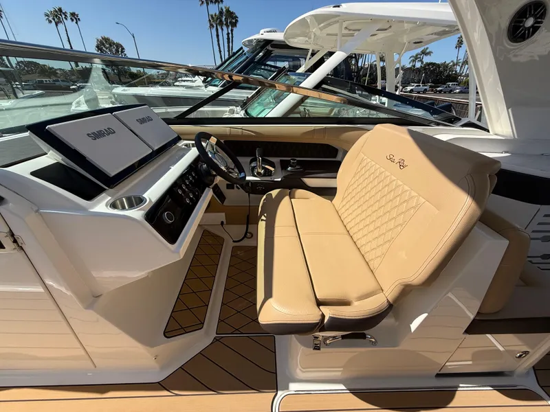 Slide: The Image of 2025 Sea Ray SLX 310 OB boat interior with tan seating and modern dashboard. - 11
