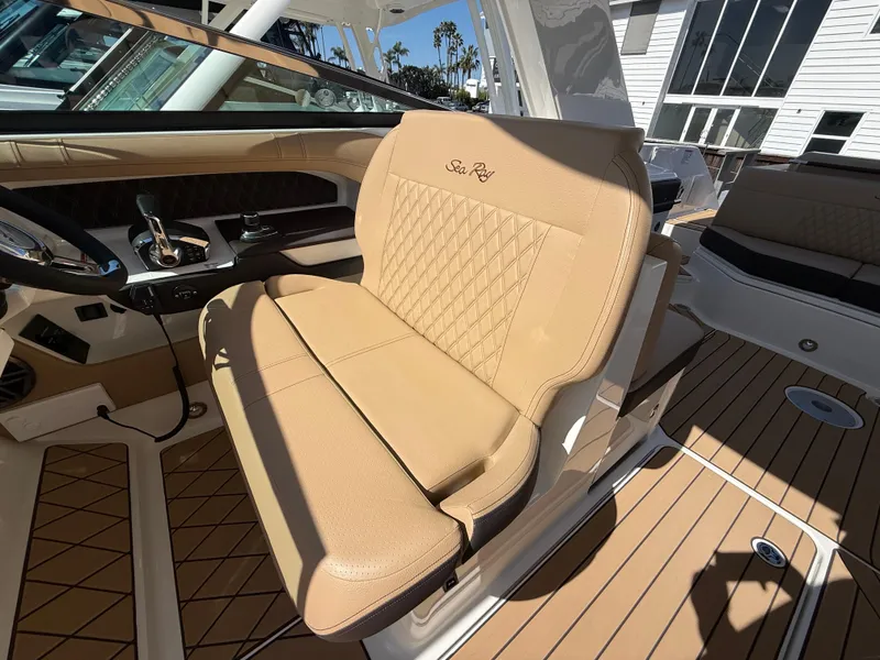 Slide: The Image of 2025 Sea Ray SLX 310 OB boat interior with tan leather seating and modern dashboard. - 12