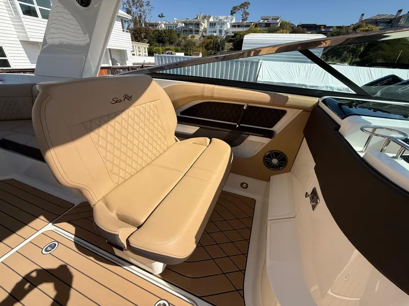 Slide: The Image of 2025 Sea Ray SLX 310 OB boat interior with tan leather seating and wood flooring. - 14