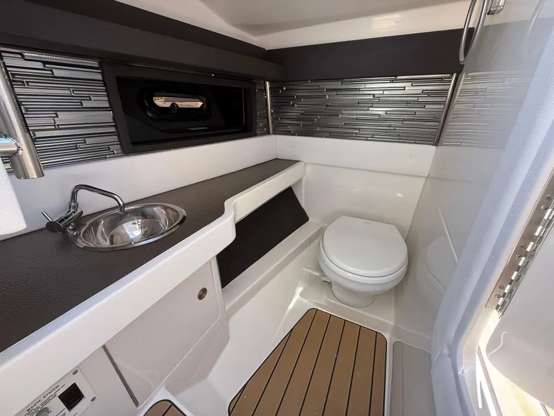 Slide: The Image of 2025 Sea Ray SLX 310 OB boat bathroom with modern sink, toilet, and stylish backsplash. - 15