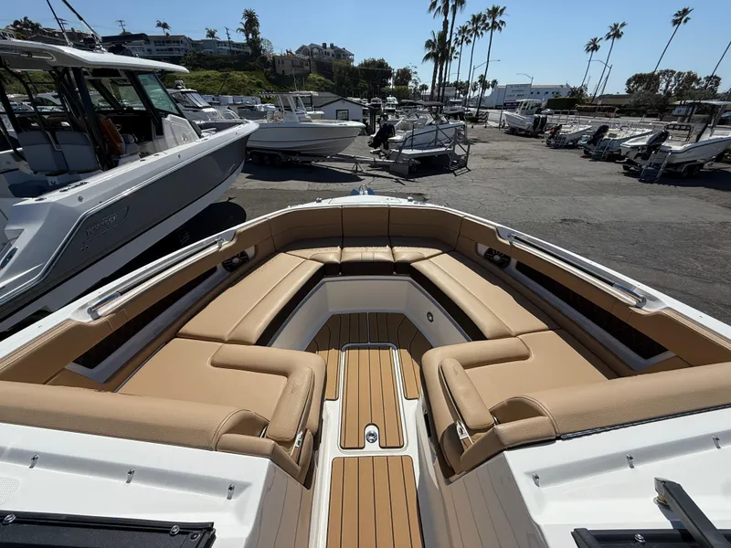 Slide: The Image of 2025 Sea Ray SLX 310 OB boat with spacious tan seating and sleek design in a marina. - 16