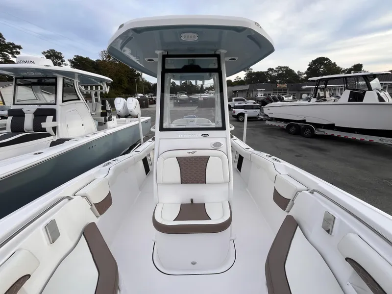 Slide: The Image of 2025 Tidewater 232 LXF boat interior with seating and console, docked at marina. - 12