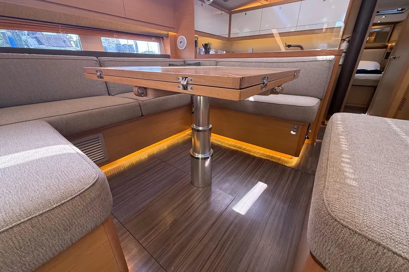 Slide: The Image of Interior of 2022 Dufour 530 yacht, featuring elegant seating and a wooden table. - 10