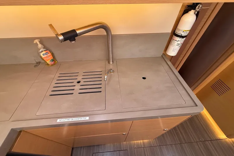 Slide: The Image of Modern kitchen sink area on 2022 Dufour 530 yacht with faucet and fire extinguisher. - 16