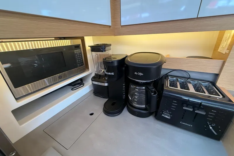 Slide: The Image of Modern kitchen appliances on a 2022 Dufour 530 yacht, including microwave, coffee maker, and toaster. - 25
