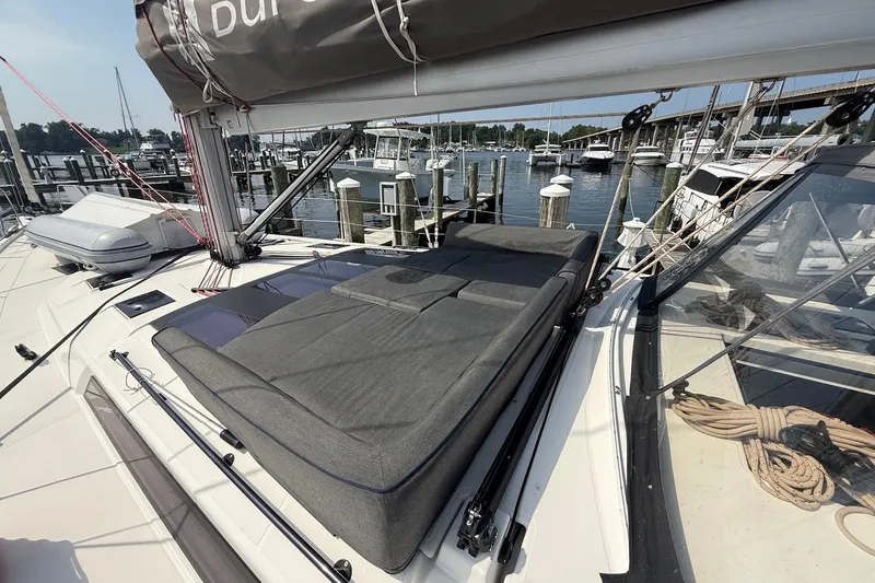 Slide: The Image of 2022 Dufour 530 yacht with cushioned deck, docked at marina with boats and bridge. - 38