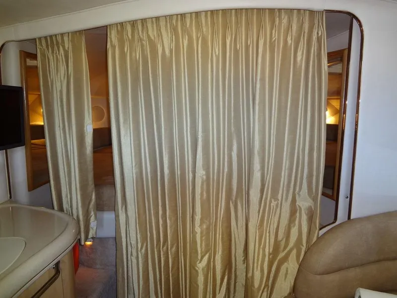 Slide: The Image of Interior of 2000 Sea Ray 340 Sundancer with beige curtains and cozy seating area. - 32