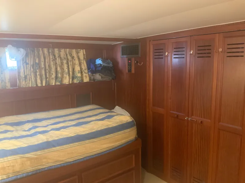 Slide: The Image of Interior cabin of a 1979 Hatteras 53 Motor Yacht with wooden closets and striped bedding. - 11