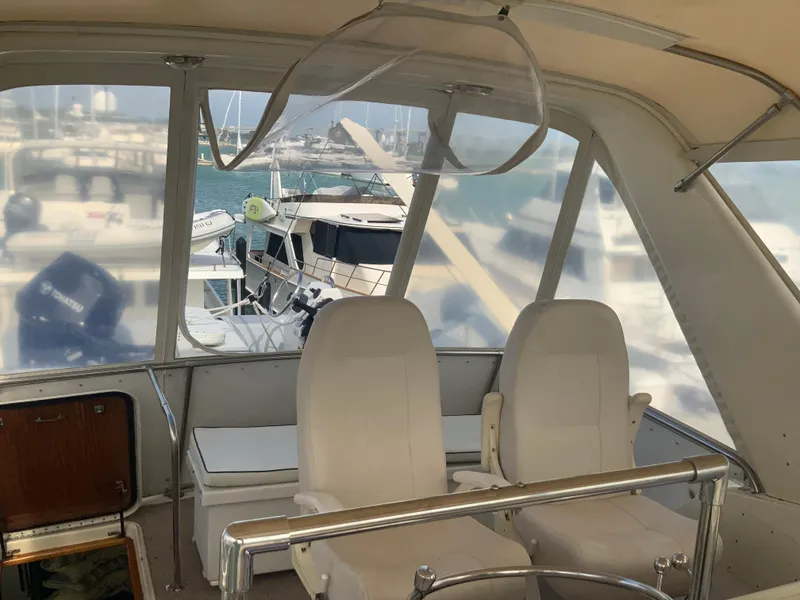 Slide: The Image of 1979 Hatteras 53 Motor Yacht interior with white seating and marina view. - 21