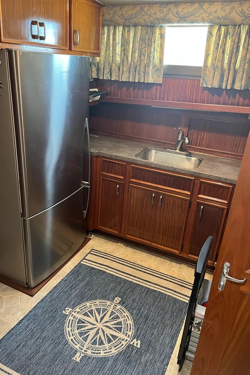 Slide: The Image of 1979 Hatteras 53 Motor Yacht kitchen with stainless steel fridge and nautical-themed rug. - 4