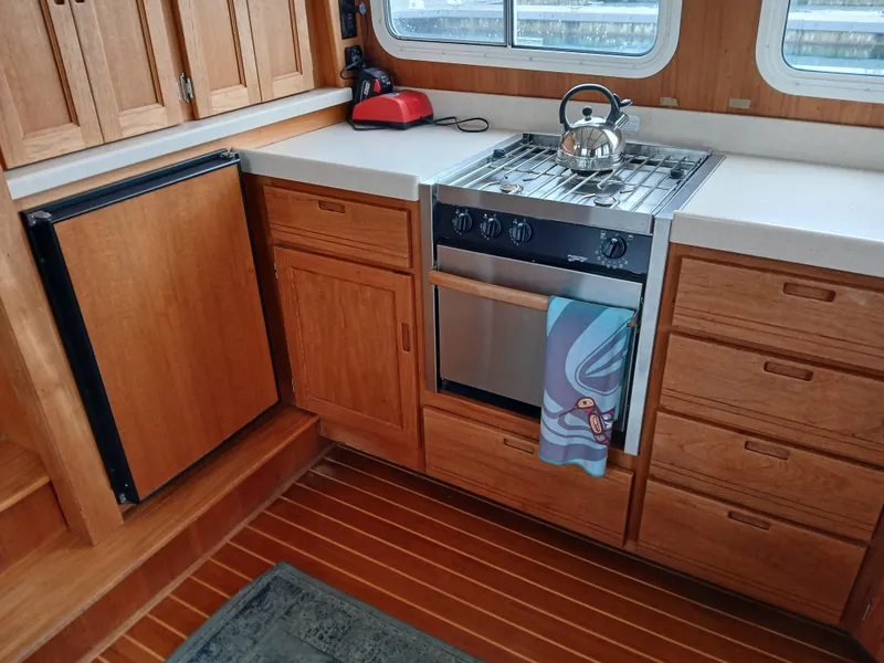 Slide: The Image of 2007 Nordic Tug 37 kitchen with wooden cabinets, stove, and kettle. - 15