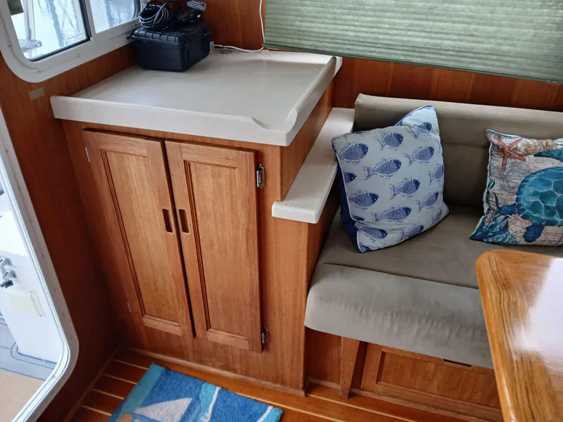 Slide: The Image of Interior of 2007 Nordic Tug 37 with wooden cabinetry, cushioned seating, and decorative pillows. - 17