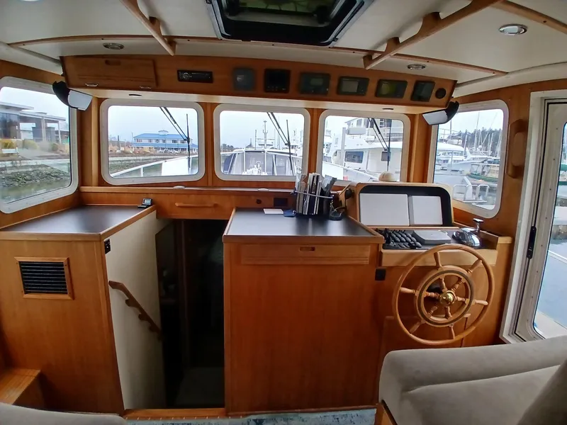 Slide: The Image of 2007 Nordic Tug 37 interior with wooden helm, large windows, and nautical controls. - 18