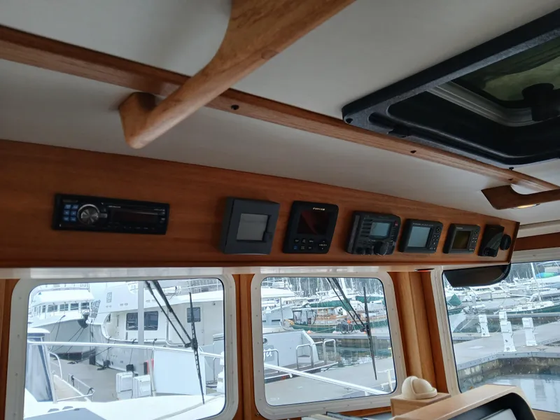 Slide: The Image of Interior view of a 2007 Nordic Tug 37, showcasing navigation instruments and marina background. - 24