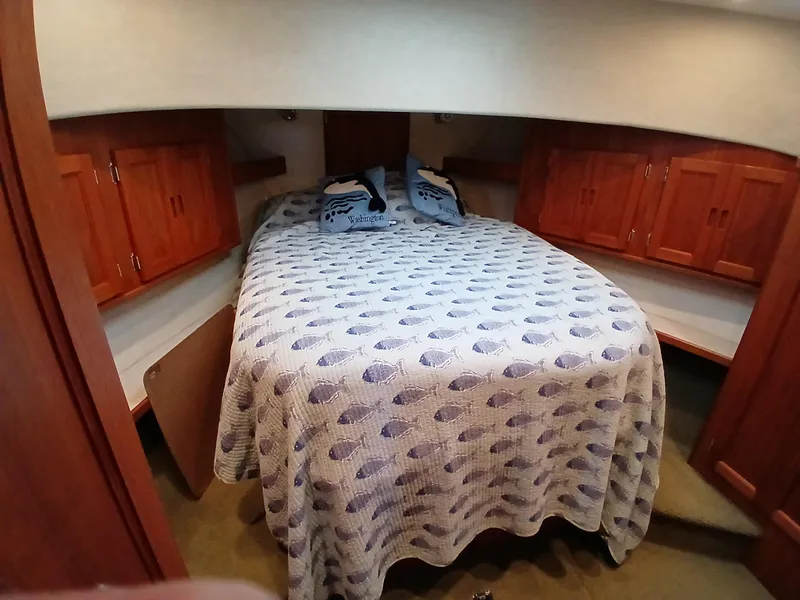 Slide: The Image of Cozy cabin bedroom in 2007 Nordic Tug 37 with wooden cabinets and patterned bedding. - 25