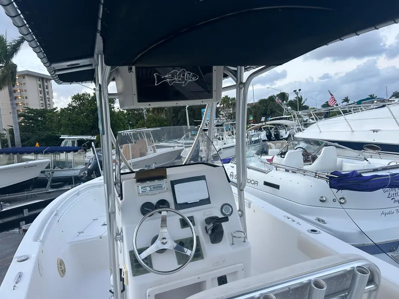 Slide: The Image of 2009 Cobia 216 Center Console boat docked at marina, featuring steering wheel and control panel. - 4