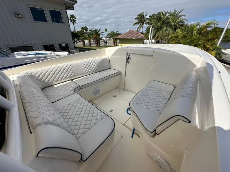 Slide: The Image of 2005 Intrepid 323 boat interior with white quilted seating, docked near palm trees. - 12