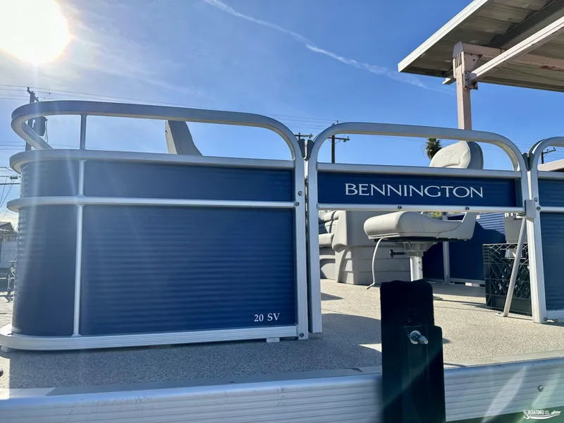 Slide: The Image of 2021 Bennington 20SV pontoon boat with blue exterior and seating, under clear sky. - 2