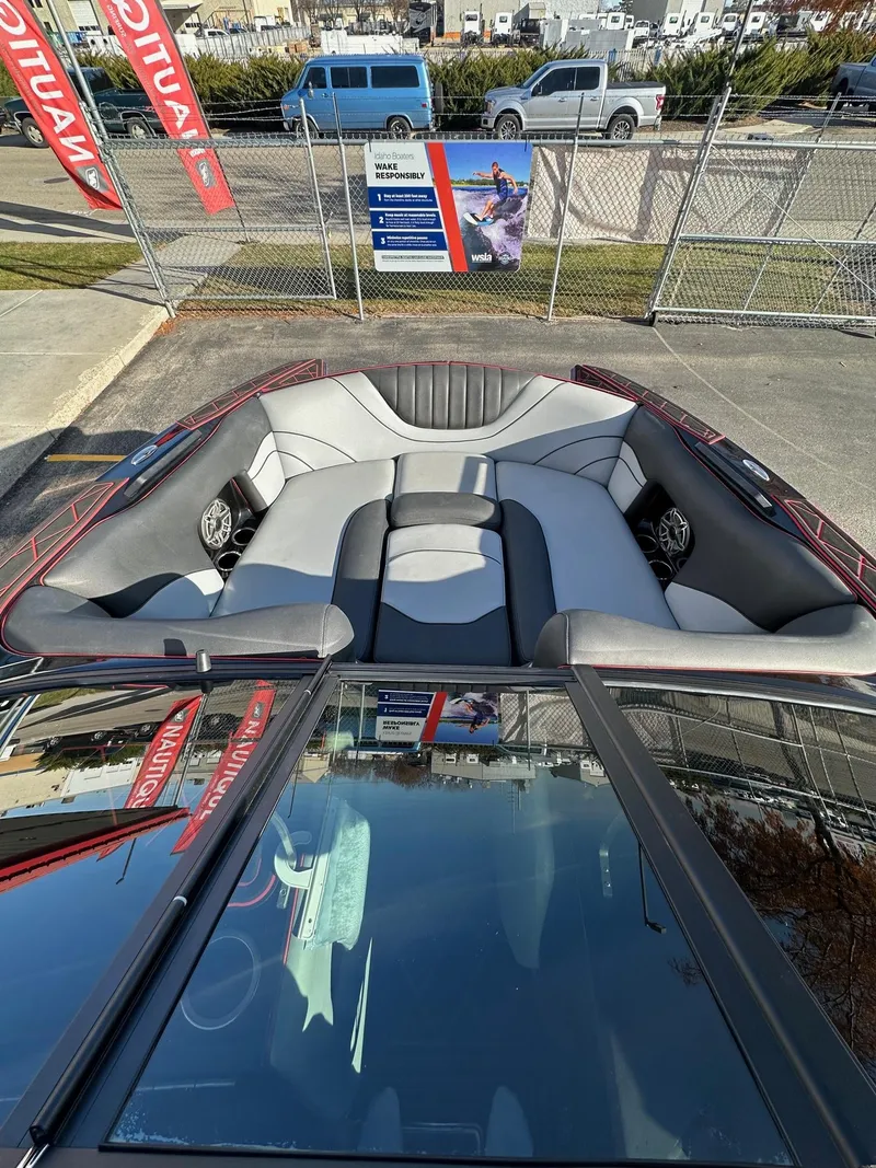 Slide: The Image of 2022 MB Tomcat F22 Alpha boat interior with gray seating and speakers, parked outdoors. - 11