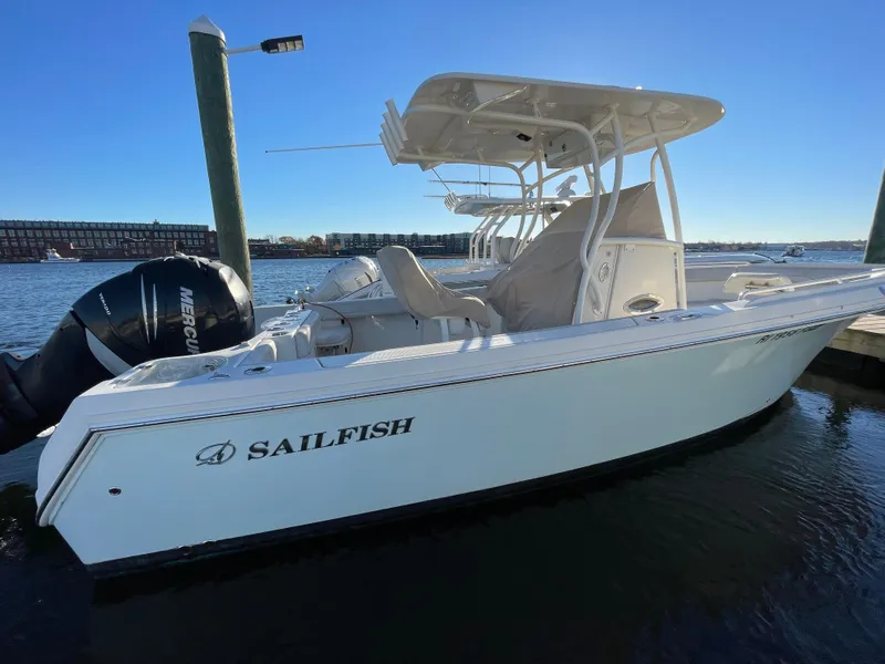 Slide: The Image of 2015 Sailfish 240 boat docked, featuring a sleek white design and Mercury outboard motor. - 1