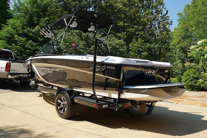 Slide: The Image of 2014 Tigé R20 boat on trailer, parked outdoors, surrounded by trees. - 10