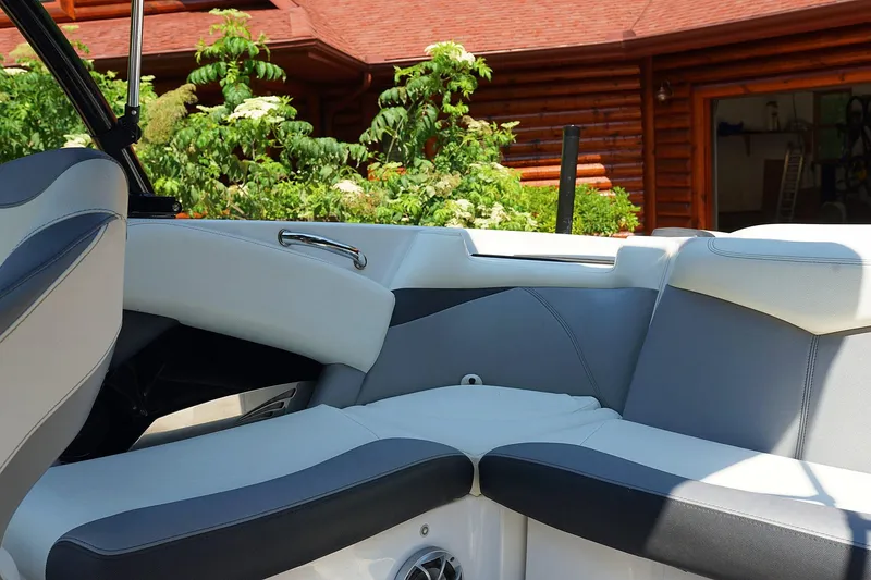 Slide: The Image of 2014 Tigé R20 boat interior with gray and white seating, near a log cabin. - 18