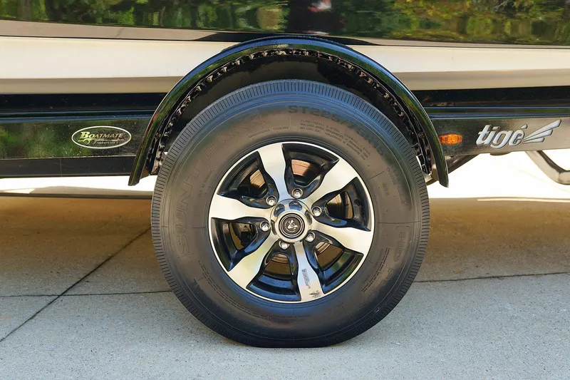 Slide: The Image of 2014 Tigé R20 boat trailer wheel with chrome rim on concrete driveway. - 19