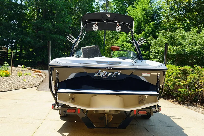 Slide: The Image of 2014 Tigé R20 boat, rear view, parked on driveway with lush greenery. - 26