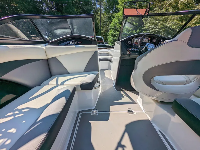 Slide: The Image of 2014 Tigé R20 boat interior with modern seating and dashboard, surrounded by lush greenery. - 33